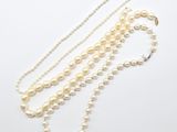 un collier de perles blanches composé de trois rangs de perles sur fond blanc