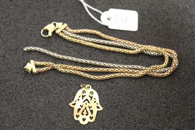 un gros plan d'un collier en or orné d'une main de Hamsa