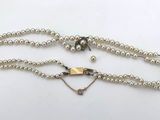 a white pearl necklace with a silver clasp and a heart charm