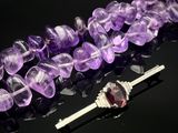 des perles d'améthorate violettes et une broche en argent sur un fond noir