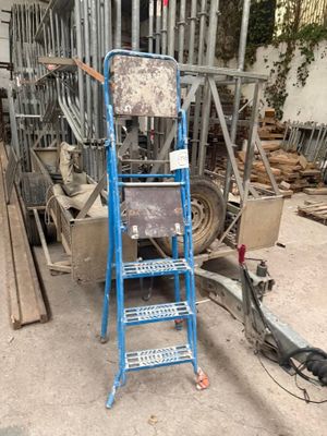 a blue ladder that is standing next to a pile of wood