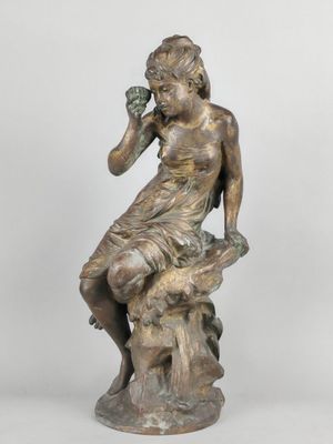 an antique bronze statue of a woman sitting on a tree stump