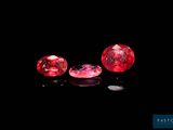three ruby colored diamonds on a black surface