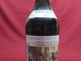 an old bottle of wine sitting on top of a red table