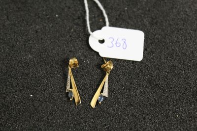 une paire de boucles d'oreilles posée sur une surface noire, avec une étiquette de prix