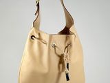 a person holding a beige purse with a chain hanging from it