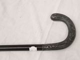 a black cane with a handle on a white sheet