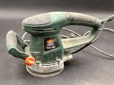 an image of a green electric sander on a black surface