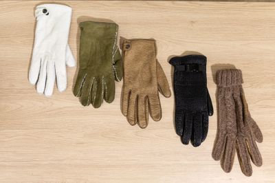 four pairs of gloves are lined up on a wooden surface
