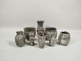 several silver vases sitting on a white surface with a white background