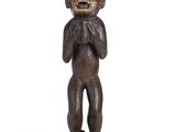 an image of a wooden statue of a monkey holding his hands to his mouth