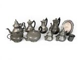 a lot of silver teapots and cups on a white surface