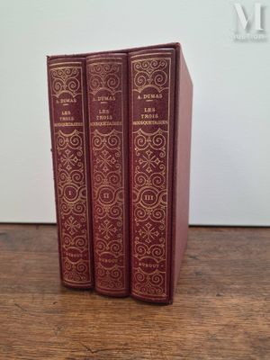 trois livres rouges posés sur une table en bois près d'un mur blanc