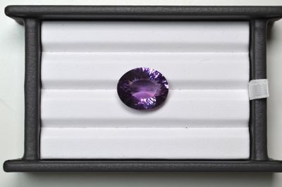 des pierres précieuses améthystes dans un écrin noir posé sur une surface blanche