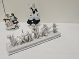 plusieurs figurines représentant des femmes et des animaux posées sur une table blanche