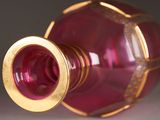 a red glass vase with a gold rim sitting on a table