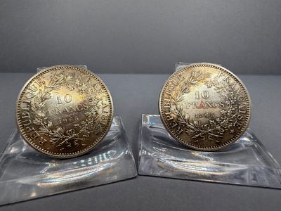 deux pièces d'or posées sur un socle transparent, sur une table