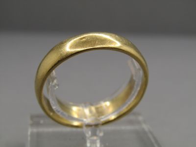 un gros plan d'une bague en or posée sur un socle transparent