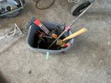a bucket full of tools sitting on the ground