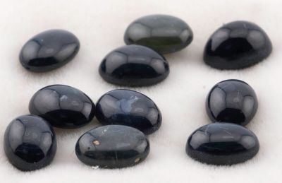 Plusieurs pierres noires sont disposées sur une surface blanche