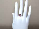 a hand with a ring on it that has a red stone on it