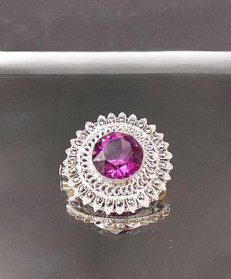 bague en argent avec une pierre rose entourée de diamants sur un fond noir