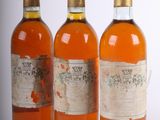 trois bouteilles de vin posées les unes à côté des autres sur une surface blanche
