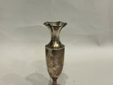 un vase en argent posé sur une surface blanche