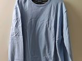 une chemise bleue à manches longues suspendue à un cintre contre un mur