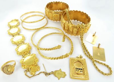 Plusieurs bijoux en or sont disposés sur une surface blanche
