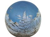 a glass ornament with a picture of a snowy mountain scene on it