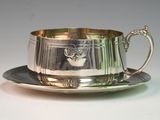 silverplated tea cup and saucer on a saucer on a white surface