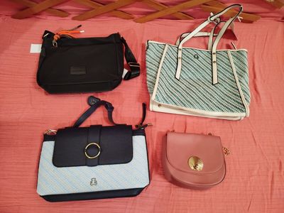 three purses and a handbag sitting on a bed