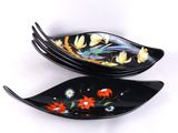 deux assiettes noires ornées de fleurs et de feuilles sur un fond blanc