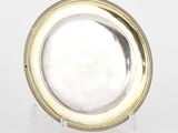 une assiette en argent bordée d'or, posée sur un socle transparent