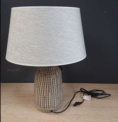 une lampe posée sur une table, dont le cordon est branché