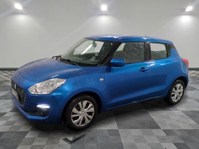 Une Suzuki Swift bleue est garée sur un sol à damier.