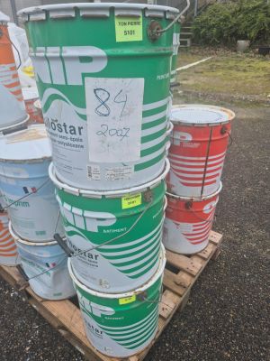 Plusieurs seaux de peinture sont empilés sur une palette dans un parking