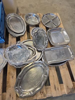 de nombreux plateaux en argent posés sur une palette dans un entrepôt