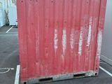 a red container sitting in the middle of a parking lot