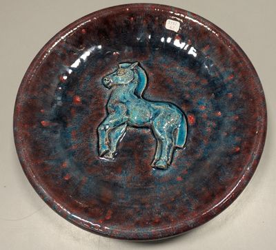 une assiette sur laquelle est représenté un cheval, posée sur une table