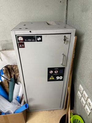 une armoire métallique sur laquelle est accrochée une pancarte, à côté d'une poubelle