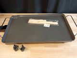 une grille noire munie d'un manche en bois, posée sur une table en bois