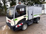 un petit camion garé sur un terrain en terre battue