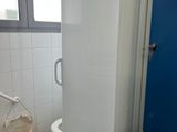 a white refrigerator in a bathroom next to a blue door