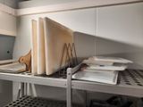 a stack of books on a metal shelf in a kitchen