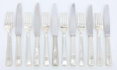 cinq fourchettes et un couteau sur une table blanche
