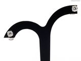 a pair of earrings that are on a black stand