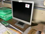 un écran d'ordinateur posé sur un bureau recouvert d'une pile de papiers