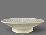 a white bowl sitting on top of a table next to a gray wall